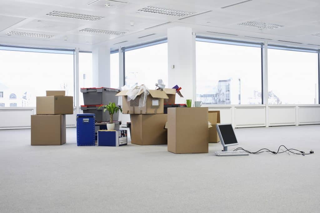 Cartons de déménagement dans un bureau presque vide, prêts pour une entreprise de déménagement commerciale